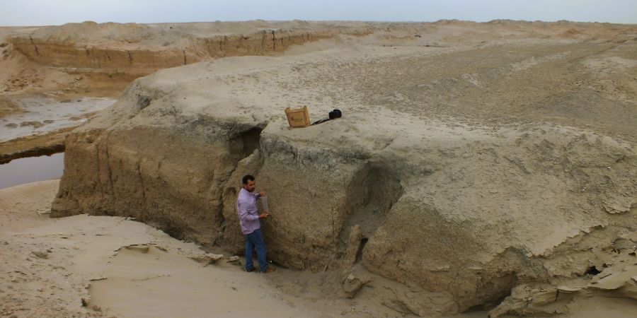 Investigador analizando un perfil de suelo en la llanura aluvial de Mesopotamia que muestra secuencias de sedimentos.