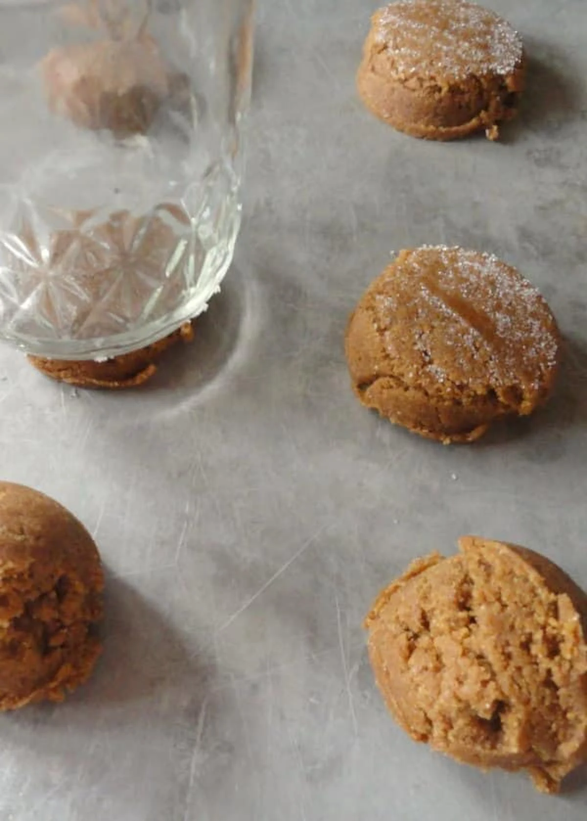 A glasses pressing Molasses Cookie Dough balls into cookie discs.