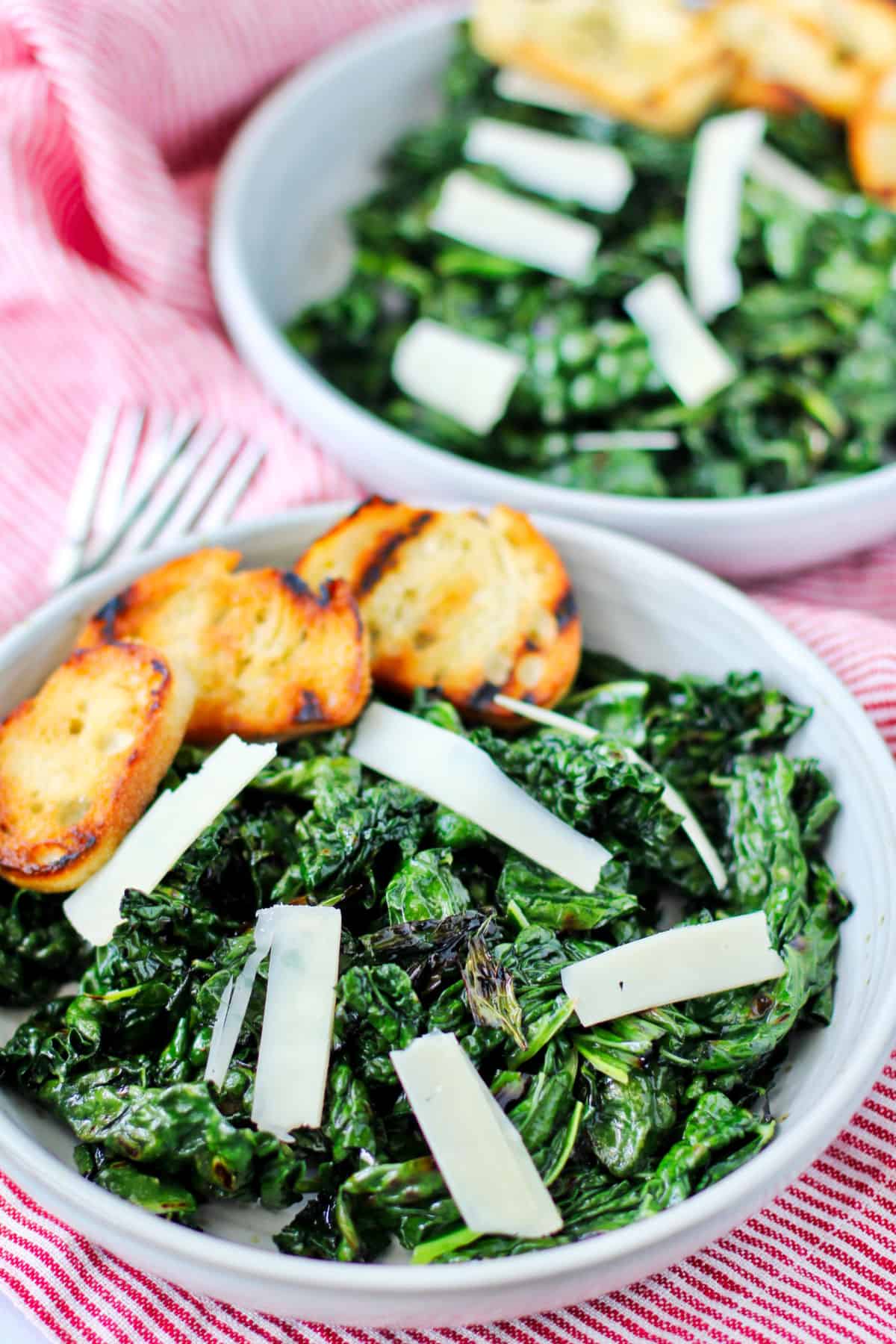 Grilled kale salad with croutons and shaved parmesan in a bowl.