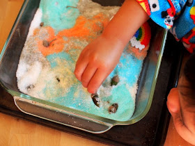 boy hiding acorns in colored salt sensory bin