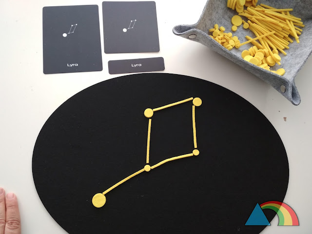Constelación Lyra construida en tapete de fieltro negro con círculos y palitos de fieltro amarillo, con tarjetas de tres partes de la constelación