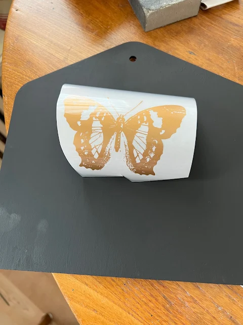 Photo of a gold butterfly decor transfer being added to a Target Dollar Spot wall envelope.