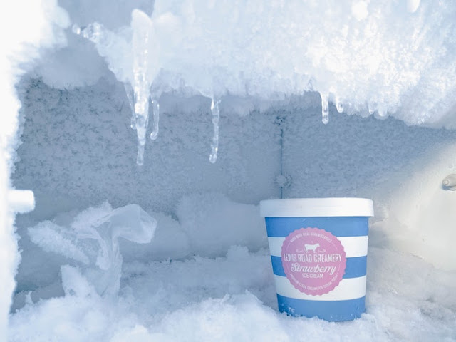 Open freezer compartment with tub of ice cream at the forefront