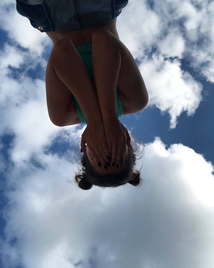 Foto aesthetic chica tapandose el rostro con chongos rodetes con el cielo y nubes de fondo