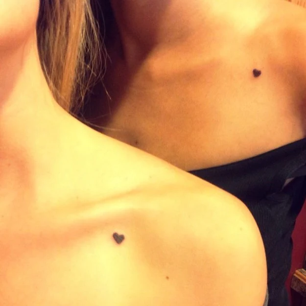 dos chicas con tatuajes de un corazon muy pequeño en el hombro
