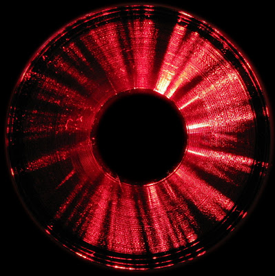 [Image: A vinyl record illuminated very unevenly with laser beams projected radially, towards the center.]