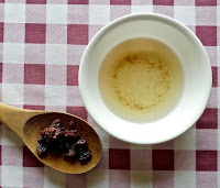 raisins on a spoon with a bowl of raisin water 