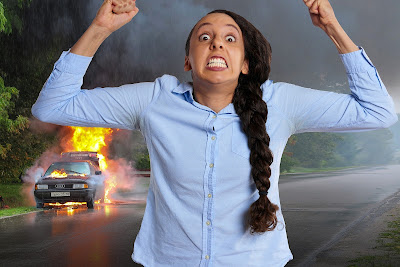 Car in flames and angry woman clutching fist in air