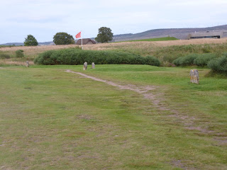 Culloden Battlefield met in de verte een rode vlag en het bezoekerscentrum