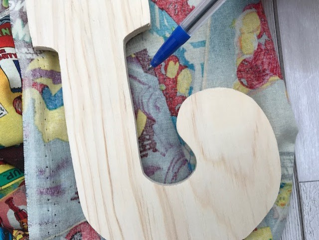 Wooden letter laid on fabric, being drawn around