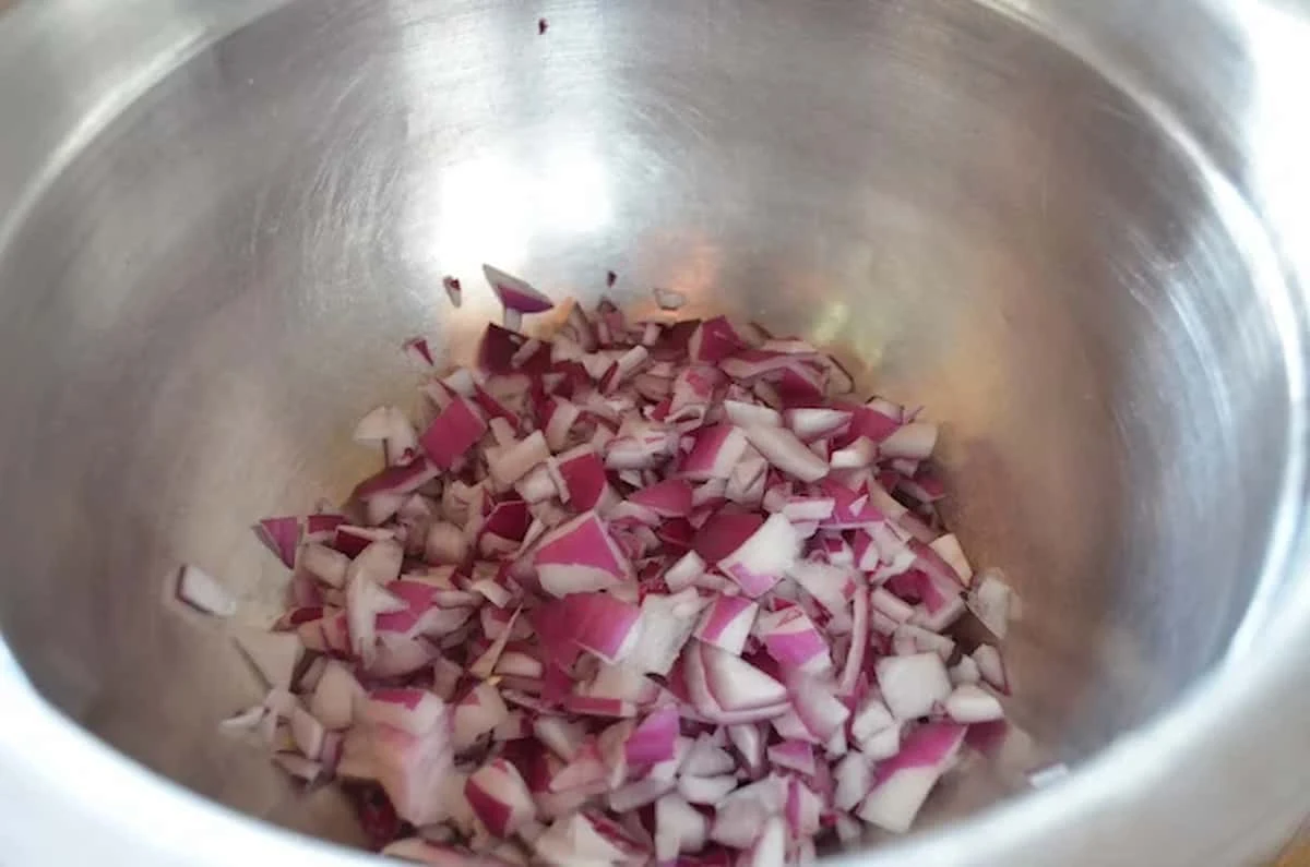 Finely diced Red Onion in a stainless steel bowl.