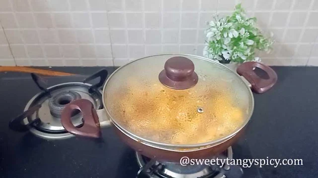 The pan is covered with a lid, and the heat is reduced to low as the Aloo Gobi simmers gently. The dish cooks for 15-20 minutes until the potatoes become tender, and occasional stirring ensures even cooking without sticking or burning.