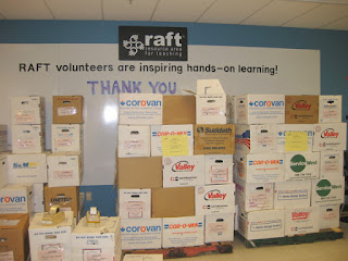 Cartons of the kits we prepared, stacked on pallets, in front of a sign that reads "RAFT volunteers are inspiring hands-on learning! Thank you", Resource Area for Teachers, Sunnyvale, California