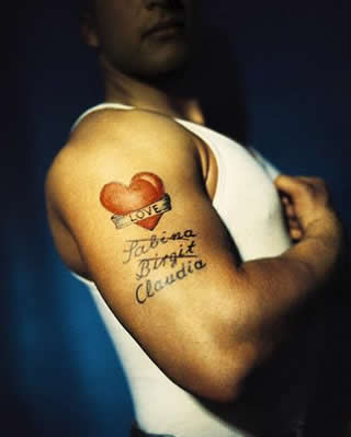 A man showing his big red heart tattoo on his upper arm with her girl 