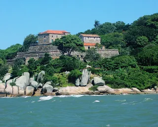 Fuerte en la ladera del morro a orillas del mar, con distintas terrazas, paredes de roca y techos de tejas portuguesas.