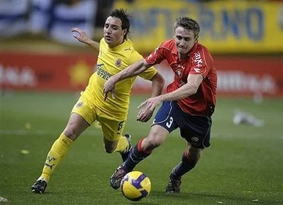 Villarreal winger Santi Cazorla fights for the ball with Osasuna's Monreal