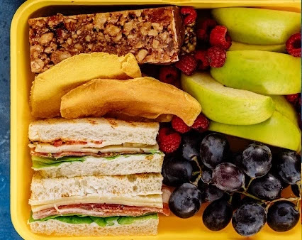 fresh mixed fruits in a yellow color tray with some sandwiches