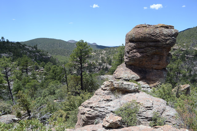 another rounded rock on a pedistal in front of some peaks above a canyon