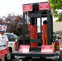Stop torture cage with hooded prisoners
