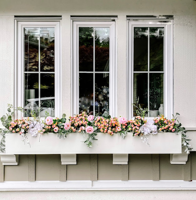 white window box with blooms and greenery 