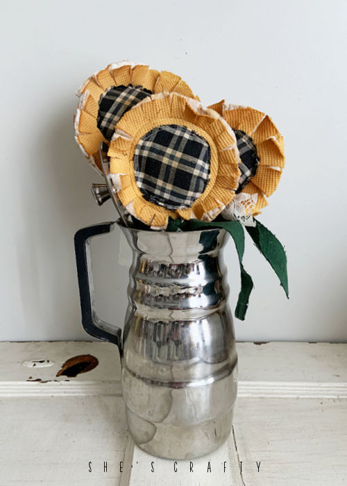 Fabric Sunflowers on vintage rulers in a coffee carafe.