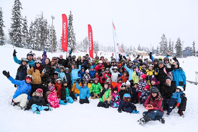 A group of skiers, posing against a snowy landscape.