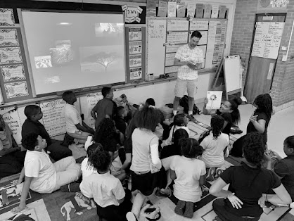 Ian Tadashi Moore reading to a classroom of young students