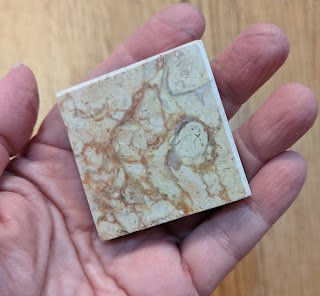 Hand holding piece of marble with cork on bottom (not visible)