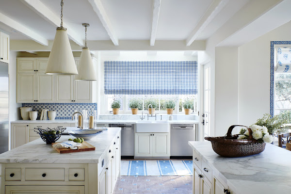 una cocina blanquecina con placa para salpicaduras azul y blanca y alfombra y tratamiento de ventanas