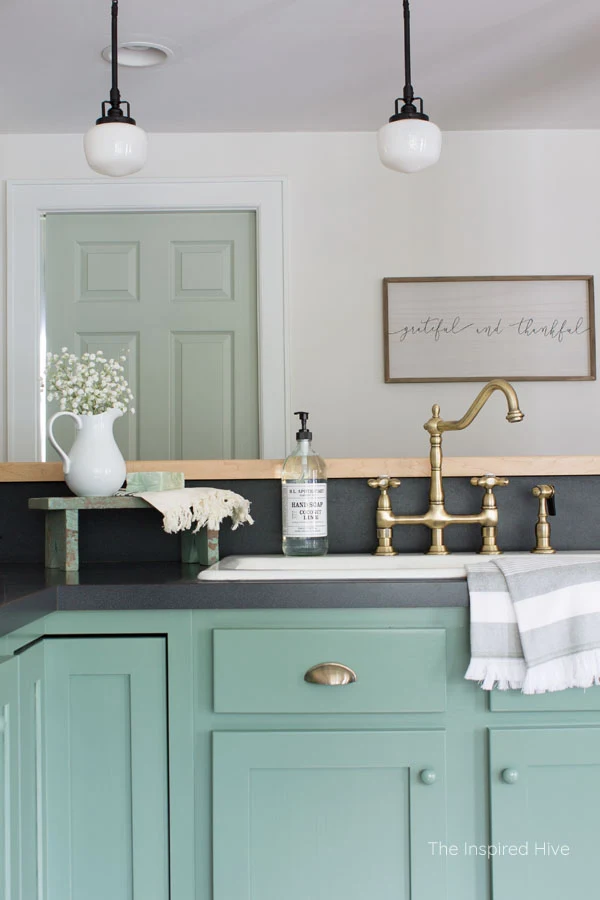 Vintage brass Heritage faucet. A cozy modern farmhouse kitchen with 1920s vintage charm. Exposed ceiling, schoolhouse lights, brass hardware, and porcelain knobs give this kitchen antique style.