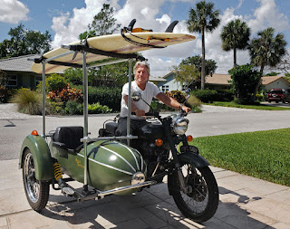 Motorcycle and sidecar with surfboard on top.