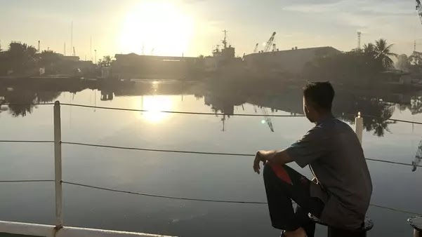 Foto seseorang duduk santai di pinggir kapal