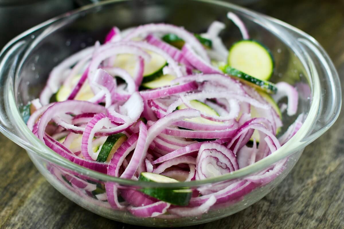 Zucchini, red onions, and kosher salt in a bowl.