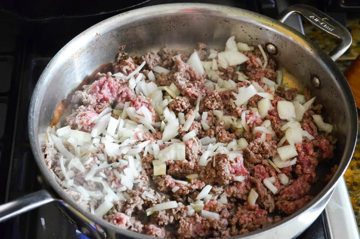 A stainless pain with olive oil, onions, and ground beef.