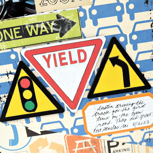 Hand-painted chipboard road sign embellishments on a teen driving scrapbook layout.