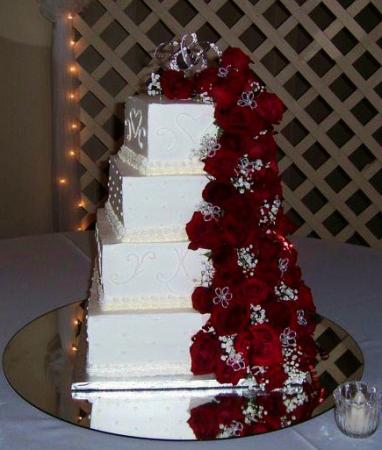 4 tier stacked square cake with many cascading red roses