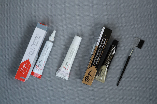 Thuya eyebrow lamination kit products laid out on a grey background. Permanent gel, neutralizer cream, regenerating cream, and a brush that came with the set.