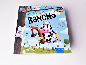 na zdjęciu karton od gry Superfarmer Rancho a na nim krowa, koń i owca bujają się na chuśtawce zawieszonej na drzewie