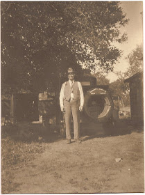 man in business suit circa 1920s standing near truck on dirt road or driveway