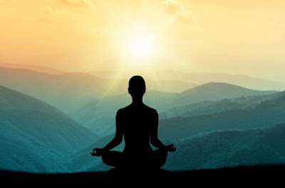 Silhouette of a person meditating under a horizon of mountains