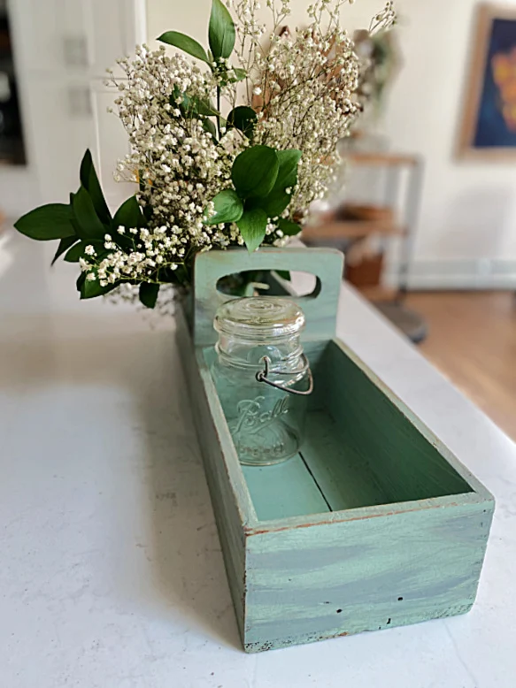green crate with flowers and jar