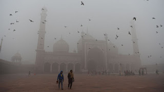 Indian visitors walk through the courtyard of Jama Masjid mosque amid heavy smog in New Delhi. (Credit: Sajjad Hussain / AFP/Getty Images) Click to Enlarge.