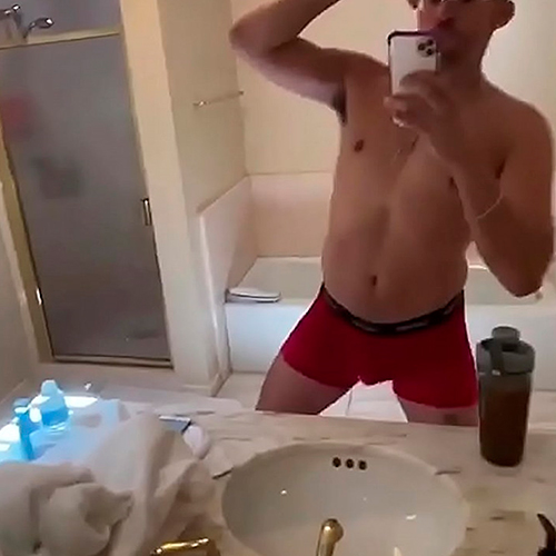 Foto do cantor Bad Bunny sem camisa e de cueca dançando no espelho
