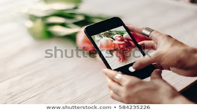 Black smart phone and brillian red flowers.