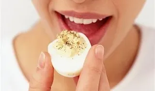a close-up of a person eating a hard boiled egg