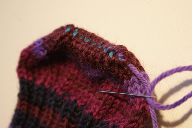  En socka i lila nyanser med en turkos söm mitt på tån /  A sock knitted in purple nuances with a turquoise seam in the middle of the toe