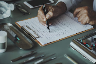 doctor's hand writing notes on a form