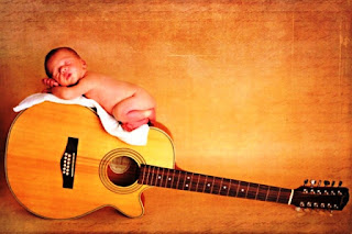 Gambar bayi lucu tidur di atas gitar