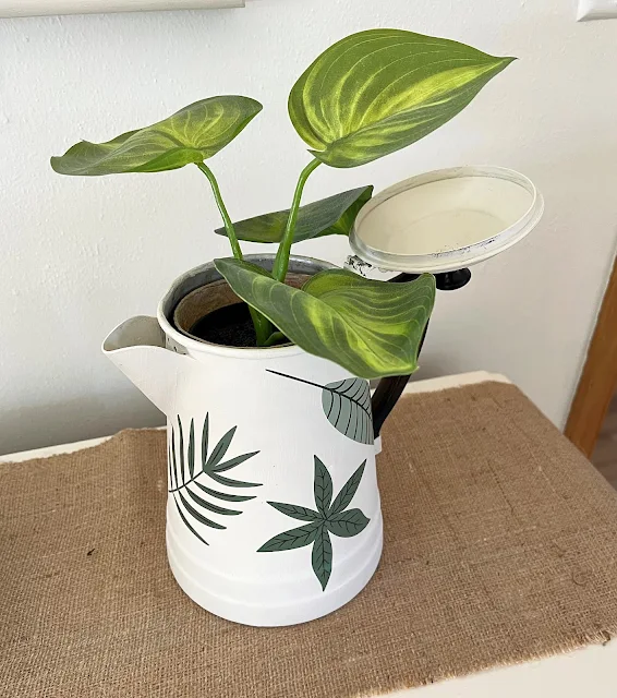 Photo of an coffeepot upcycled and repurposed with paint and decor transfers to hold plants.