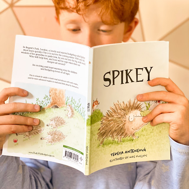 A young boy holding the book open as he reads it